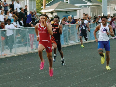 student running track against two other male athletes